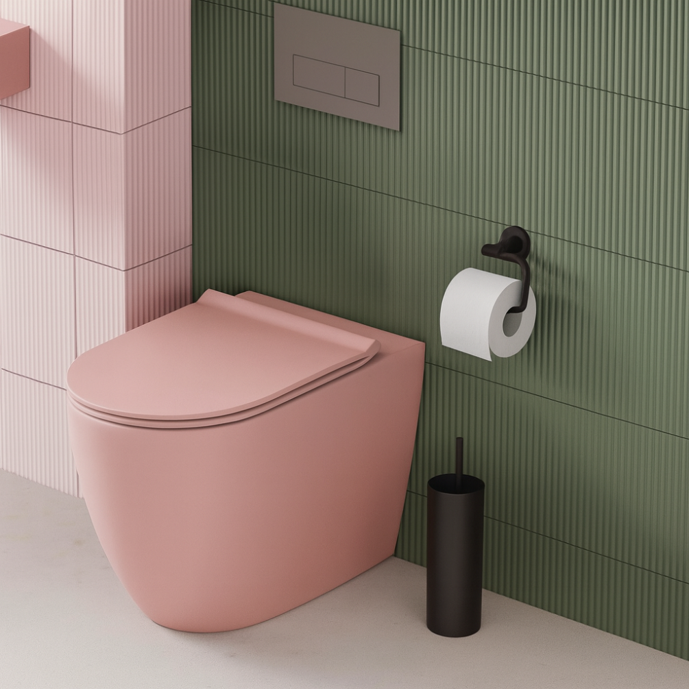 Lifestyle image of the Zero 3 Matt Pink Rimless Back To Wall Toilet & Soft Close Seat installed against a green tiled wall with toilet roll dispenser